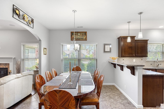 dining area featuring visible vents, baseboards, a chandelier, arched walkways, and light tile patterned floors