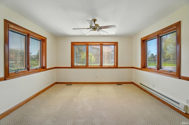 empty room featuring light colored carpet, baseboard heating, a ceiling fan, baseboards, and visible vents