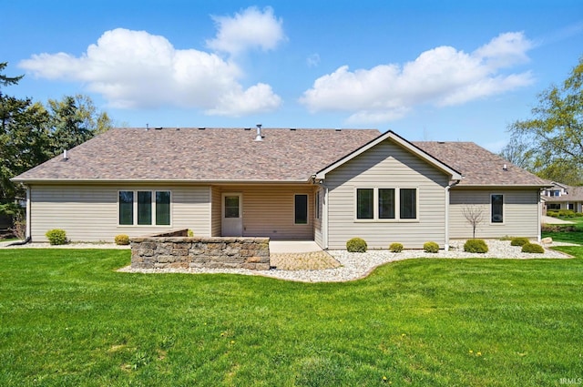 rear view of property featuring a lawn, a shingled roof, and a patio area