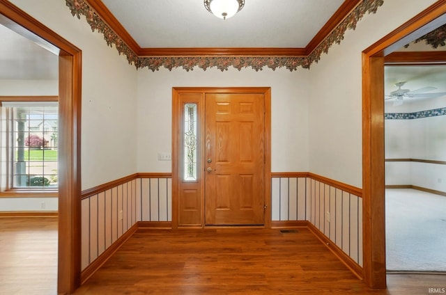 entryway with ornamental molding, a ceiling fan, and wood finished floors