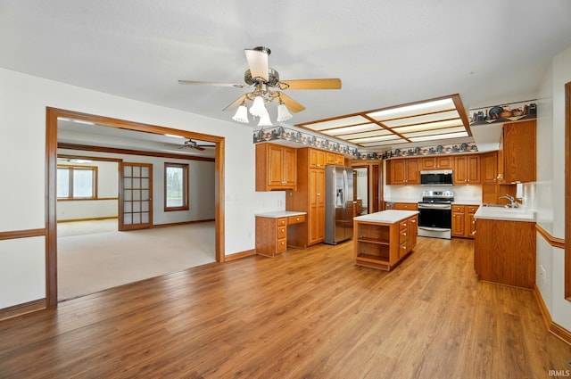 kitchen featuring brown cabinetry, open shelves, ceiling fan, a sink, and stainless steel appliances