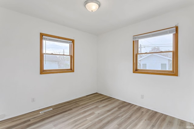 unfurnished room with light wood-type flooring and visible vents