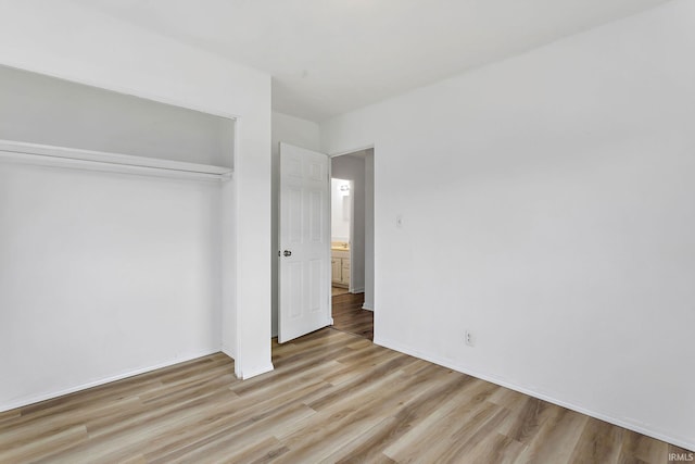 unfurnished bedroom with a closet, baseboards, and wood finished floors