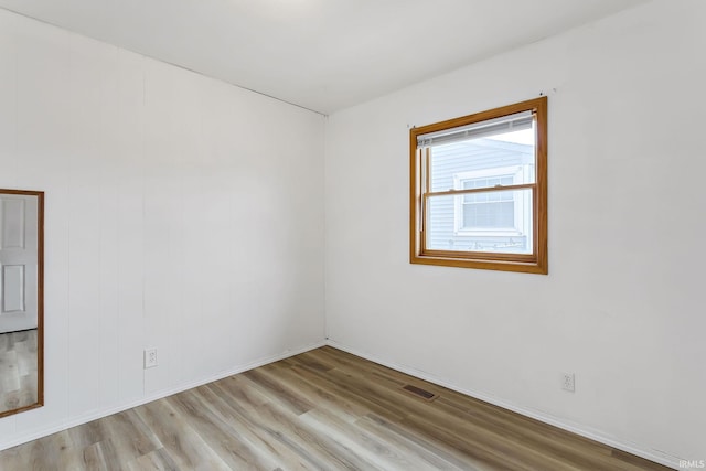 spare room with visible vents, baseboards, and wood finished floors