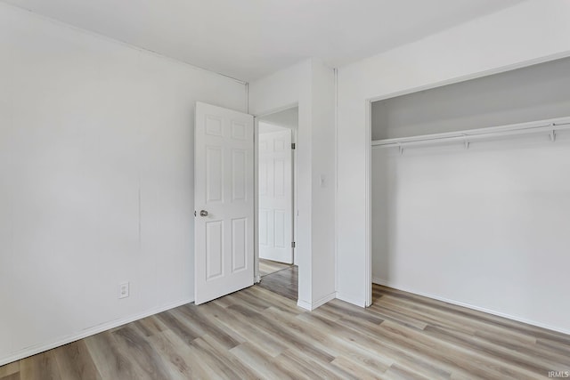 unfurnished bedroom featuring a closet, baseboards, and wood finished floors