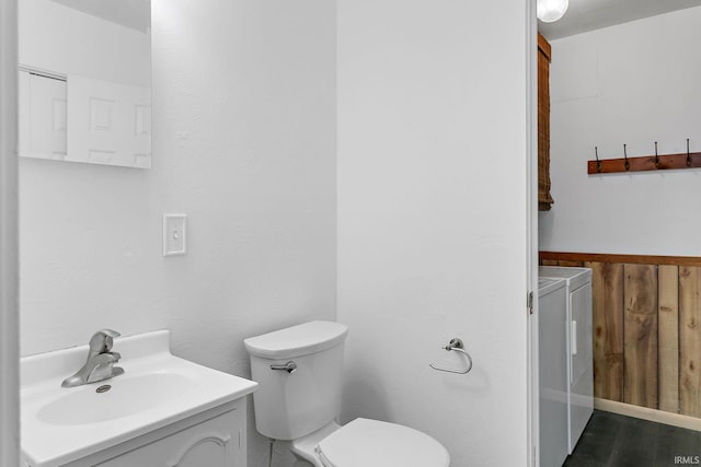 bathroom with washer and dryer, toilet, and vanity