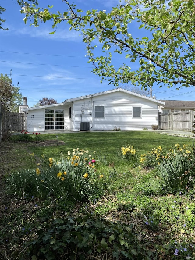 back of property with central air condition unit, a yard, and fence