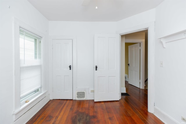 unfurnished bedroom featuring ceiling fan, dark wood finished floors, and visible vents