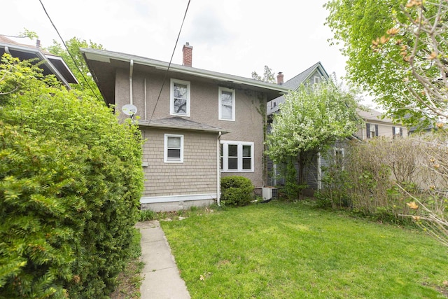 rear view of property featuring a lawn, central AC, and a chimney