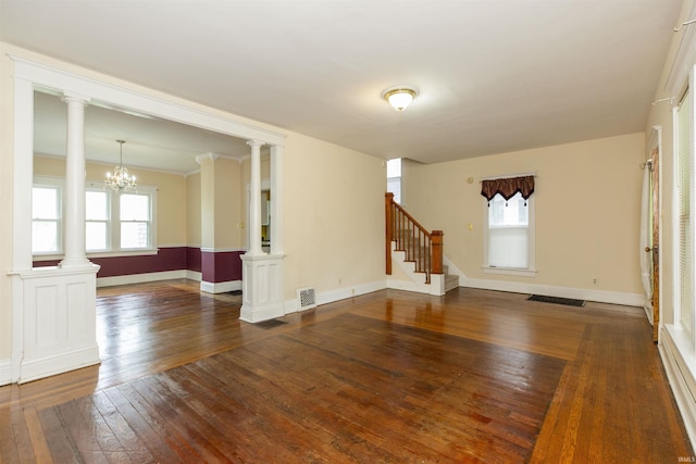 unfurnished living room featuring decorative columns, baseboards, visible vents, and dark wood finished floors