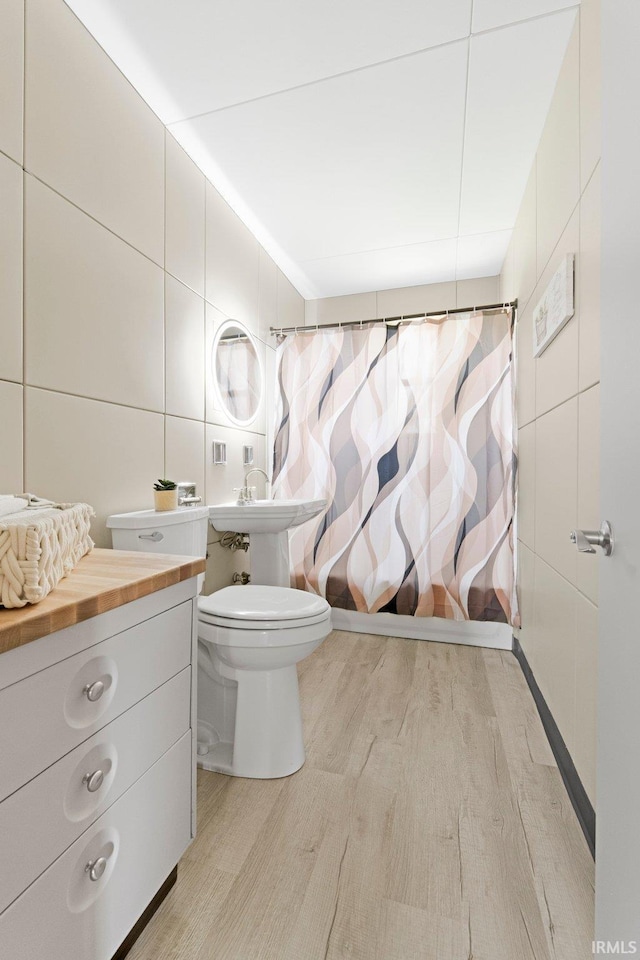 bathroom featuring tile walls, curtained shower, toilet, and wood finished floors