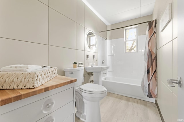 bathroom featuring tile walls, shower / bath combo, toilet, and wood finished floors