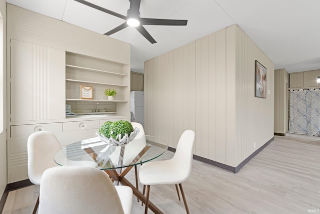 dining room featuring ceiling fan, baseboards, and light wood-type flooring