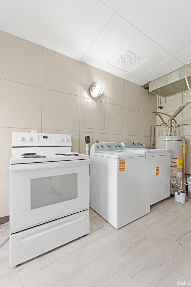 clothes washing area featuring light wood-type flooring, water heater, independent washer and dryer, and tile walls