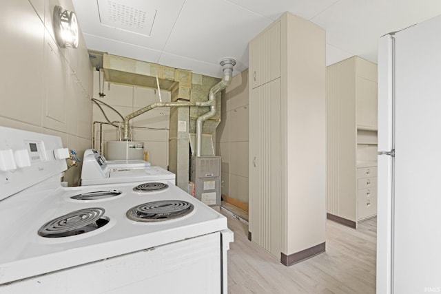 kitchen with independent washer and dryer, cream cabinets, white appliances, light wood-style flooring, and water heater