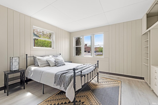 bedroom featuring light wood finished floors and a decorative wall