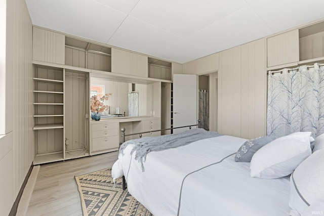 bedroom with light wood-type flooring and wood walls