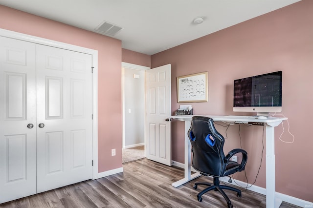 home office with baseboards, visible vents, and wood finished floors