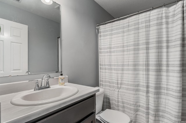 full bath with vanity, a textured ceiling, and toilet
