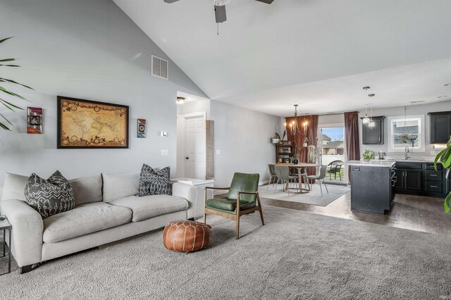 living area with visible vents, ceiling fan with notable chandelier, and high vaulted ceiling