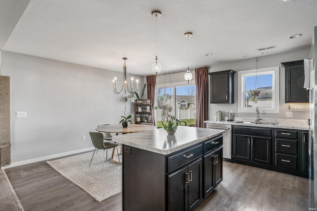 kitchen with stainless steel dishwasher, wood finished floors, light countertops, a textured ceiling, and a sink