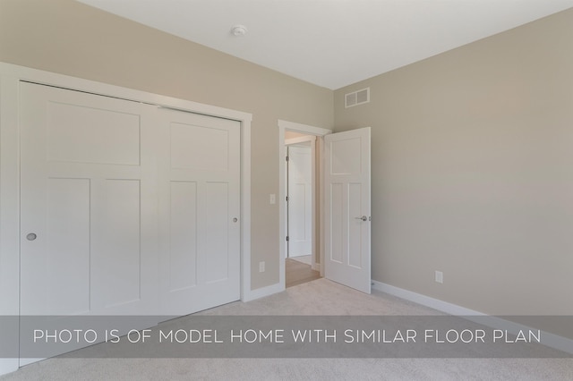 unfurnished bedroom with baseboards, visible vents, light carpet, and a closet