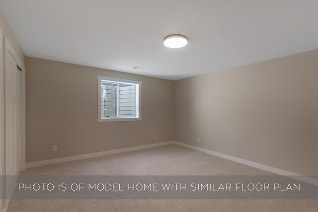 spare room with baseboards and light carpet