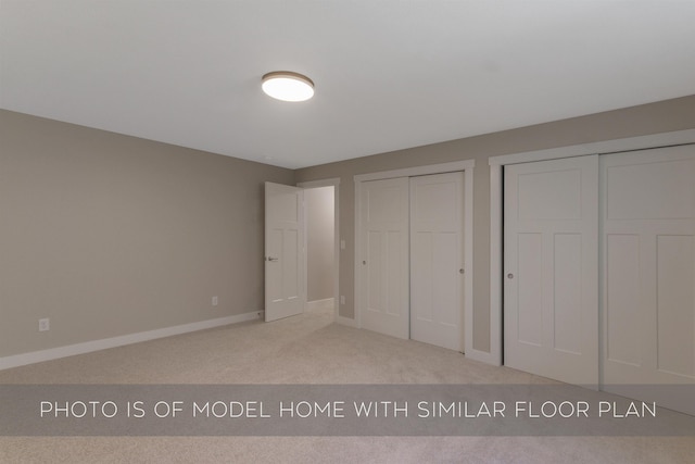unfurnished bedroom with carpet floors, baseboards, and two closets