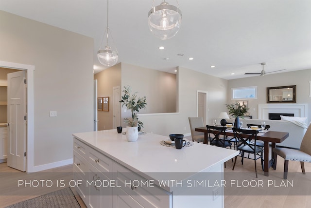 kitchen with a fireplace, baseboards, open floor plan, ceiling fan, and white cabinets