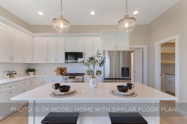kitchen featuring a center island, light countertops, tasteful backsplash, and stainless steel appliances