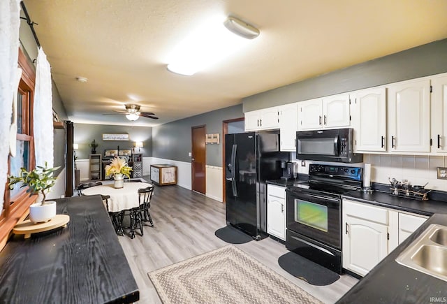 kitchen featuring dark countertops, ceiling fan, black appliances, and white cabinetry