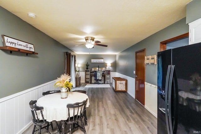 dining space featuring ceiling fan, wood finished floors, and a wainscoted wall