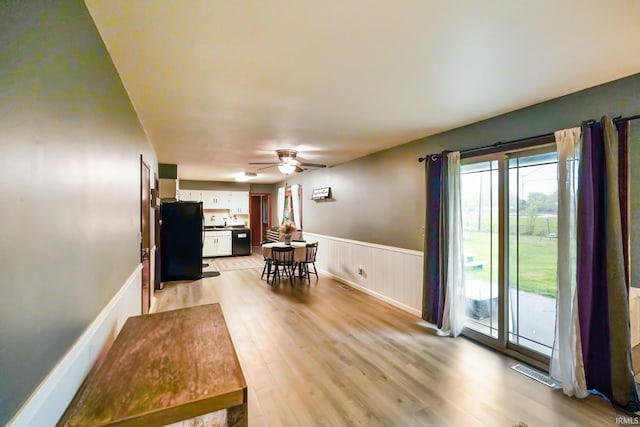 living room with a ceiling fan, wainscoting, light wood-style flooring, and visible vents