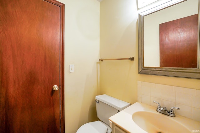 half bath with vanity, tasteful backsplash, and toilet