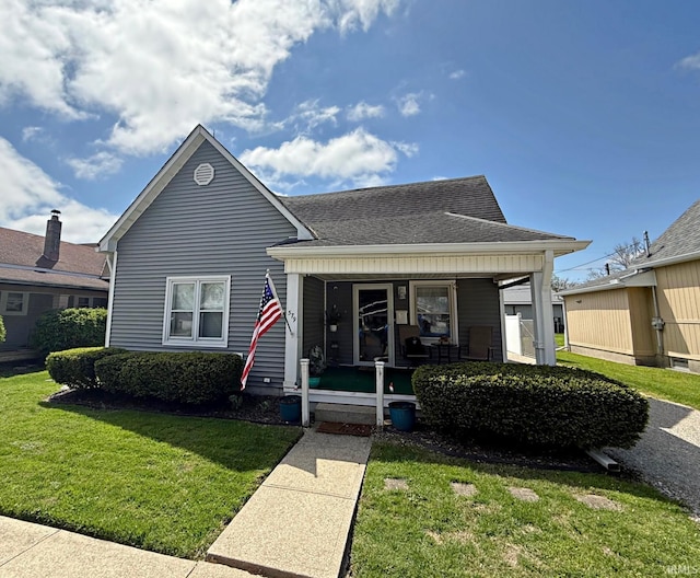 bungalow-style home featuring covered porch, a shingled roof, and a front lawn