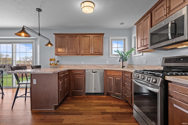 kitchen featuring appliances with stainless steel finishes, a textured ceiling, a kitchen bar, and dark wood-style floors