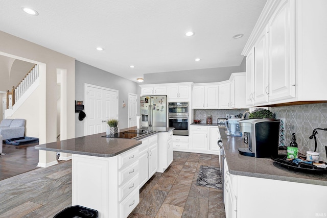 7911 N Thames Dr, Bloomington, IN 47408 - kitchen with white cabinets, stainless steel appliances, dark countertops, and decorative backsplash