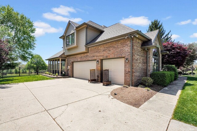 7911 N Thames Dr, Bloomington, IN 47408 - view of side of home with brick siding, roof with shingles, fence, and driveway