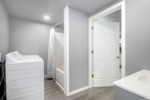 bathroom with washing machine and clothes dryer, vanity, baseboards, wood finished floors, and shower / tub combo