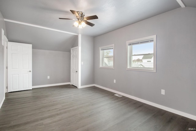 unfurnished bedroom featuring ceiling fan, visible vents, baseboards, lofted ceiling, and dark wood-type flooring