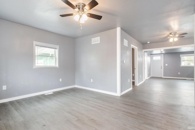 spare room featuring baseboards, ceiling fan, wood finished floors, and visible vents