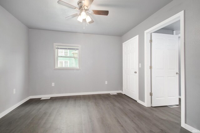 unfurnished bedroom with a ceiling fan, baseboards, and dark wood-style floors