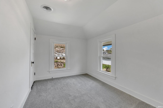 carpeted spare room featuring baseboards, visible vents, and lofted ceiling