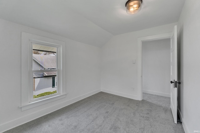 spare room with baseboards, lofted ceiling, and carpet