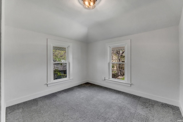 carpeted spare room with baseboards and vaulted ceiling
