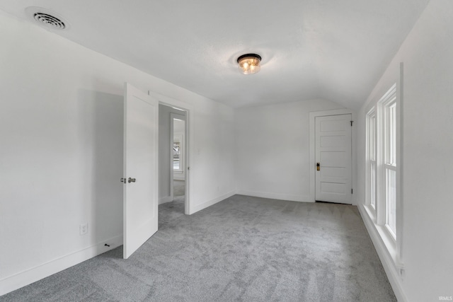 carpeted empty room with visible vents, baseboards, and lofted ceiling