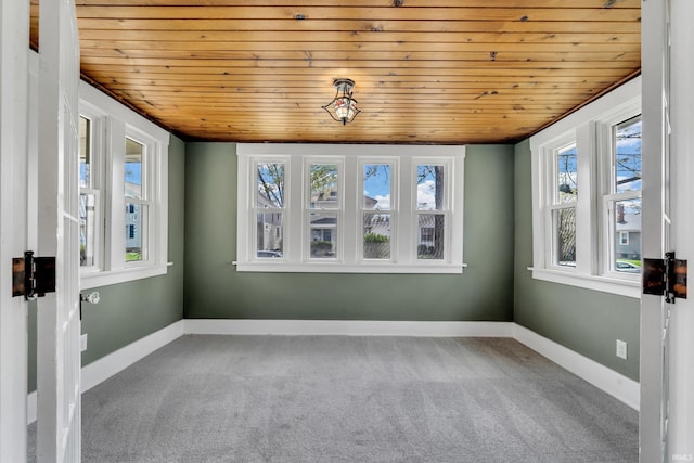 carpeted spare room with baseboards and wooden ceiling