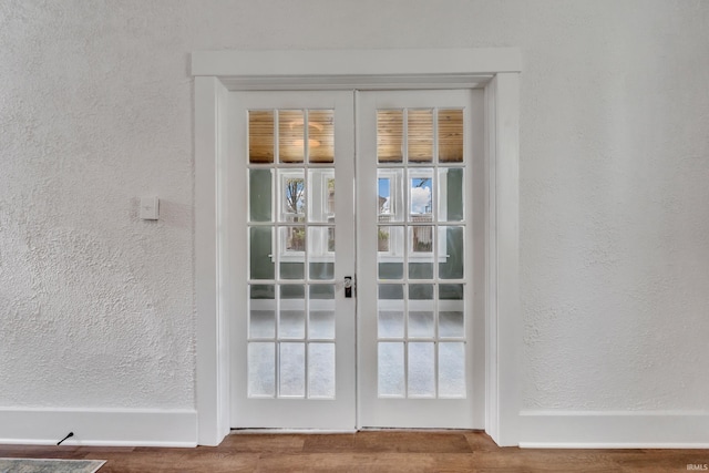 entryway featuring french doors, a textured wall, and wood finished floors