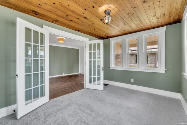 spare room featuring wood ceiling, baseboards, carpet, and french doors