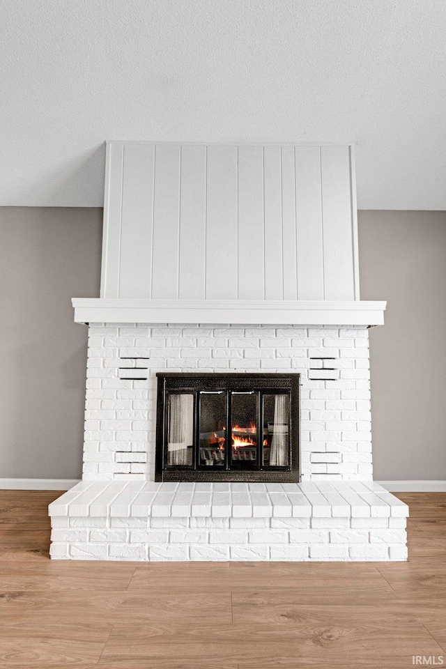 room details with a textured ceiling, baseboards, wood finished floors, and a fireplace